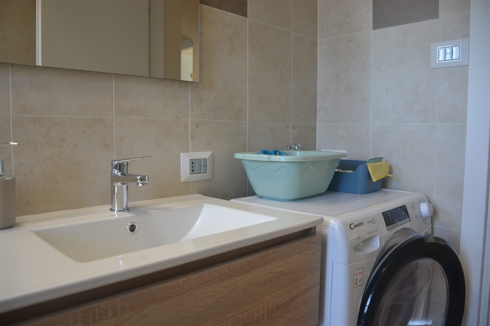 Zona bagno e lavanderia con lavabo, lavasciuga e accessori
