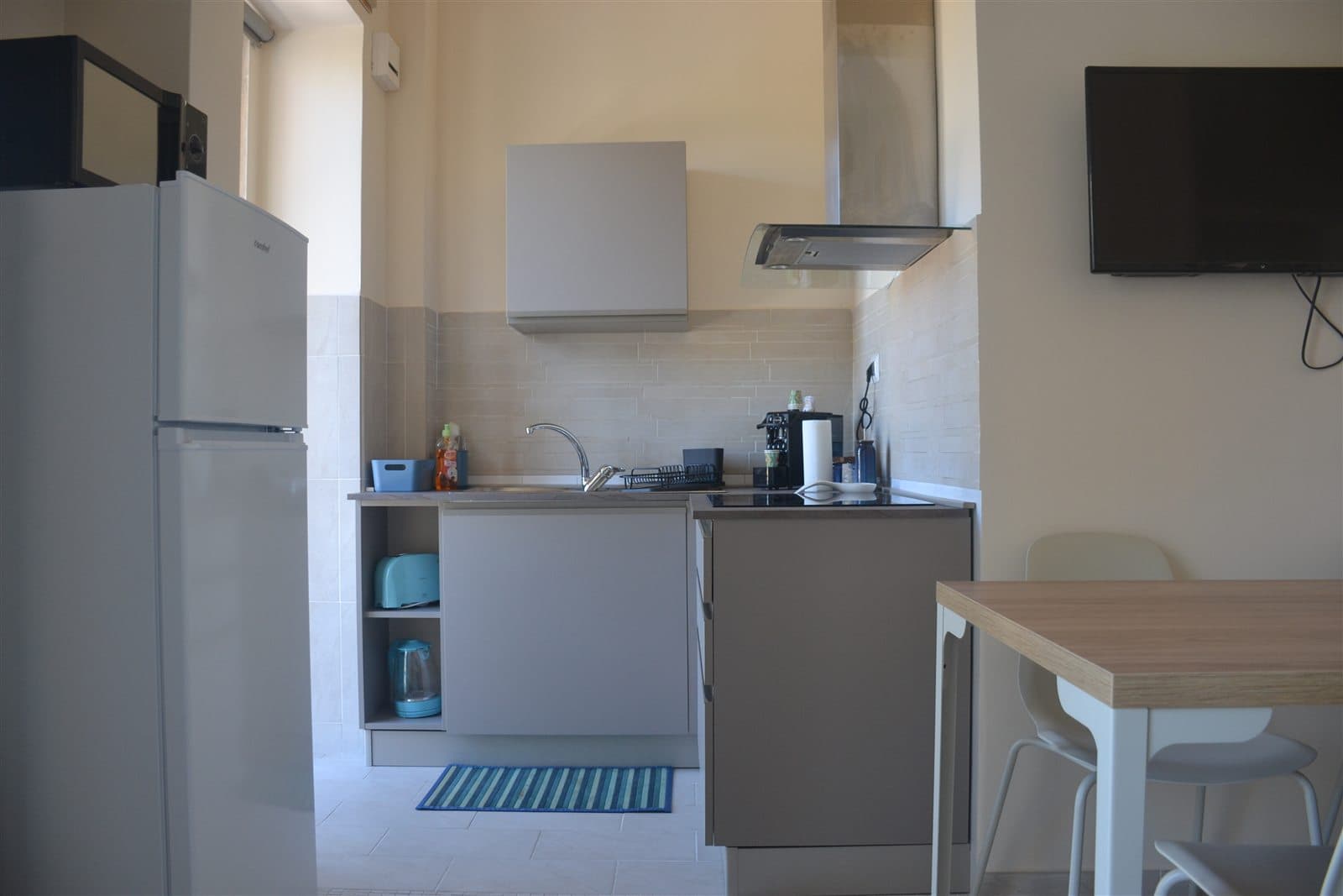 Cucina attrezzata con tavolo da pranzo e televisore